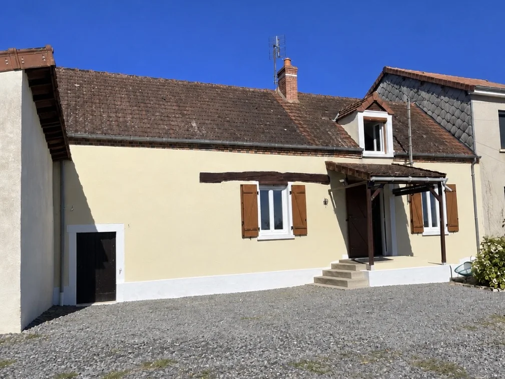 La même longère après travaux : enduit repeint couleur sable, soubassement blanc